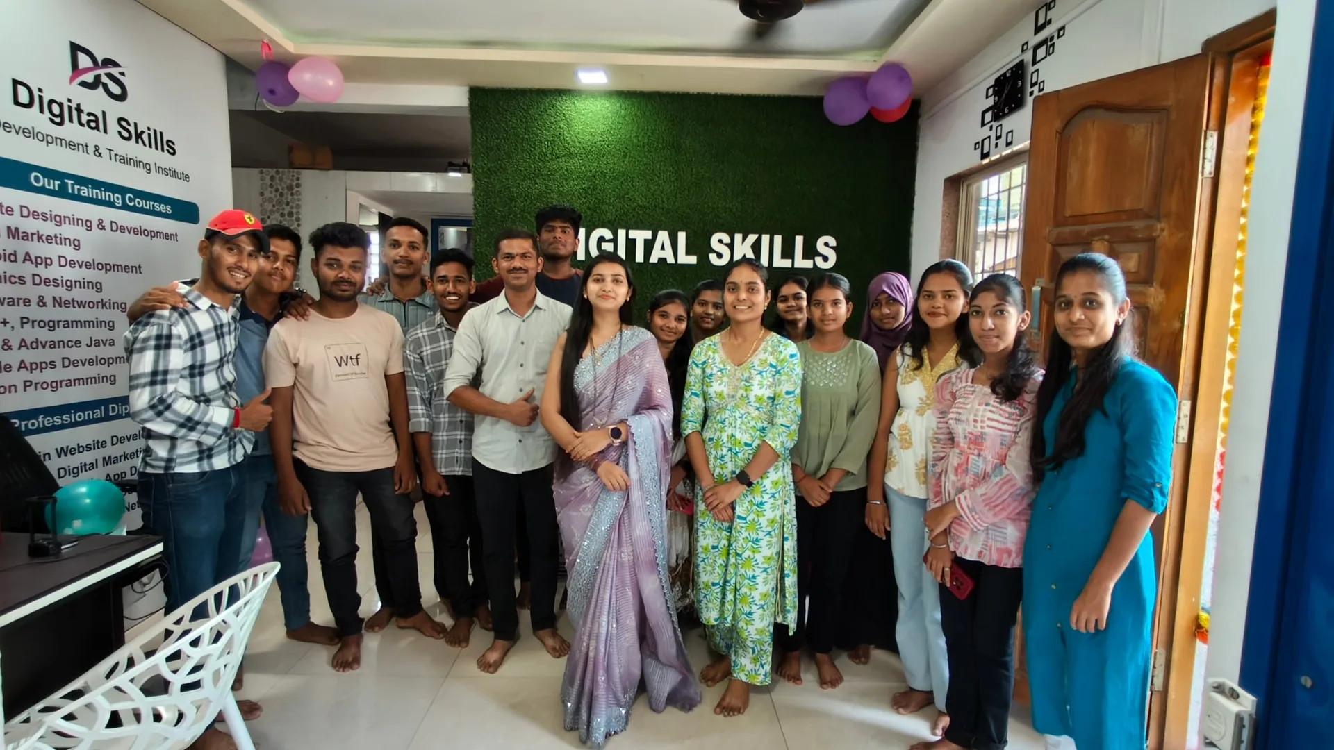 Digital Skills students and trainers celebrating in front of the green brand wall